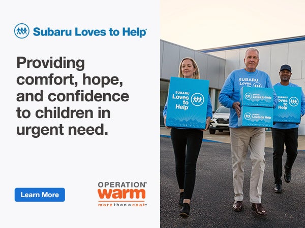 Four adults carrying boxes labeled Subaru Loves to Help.